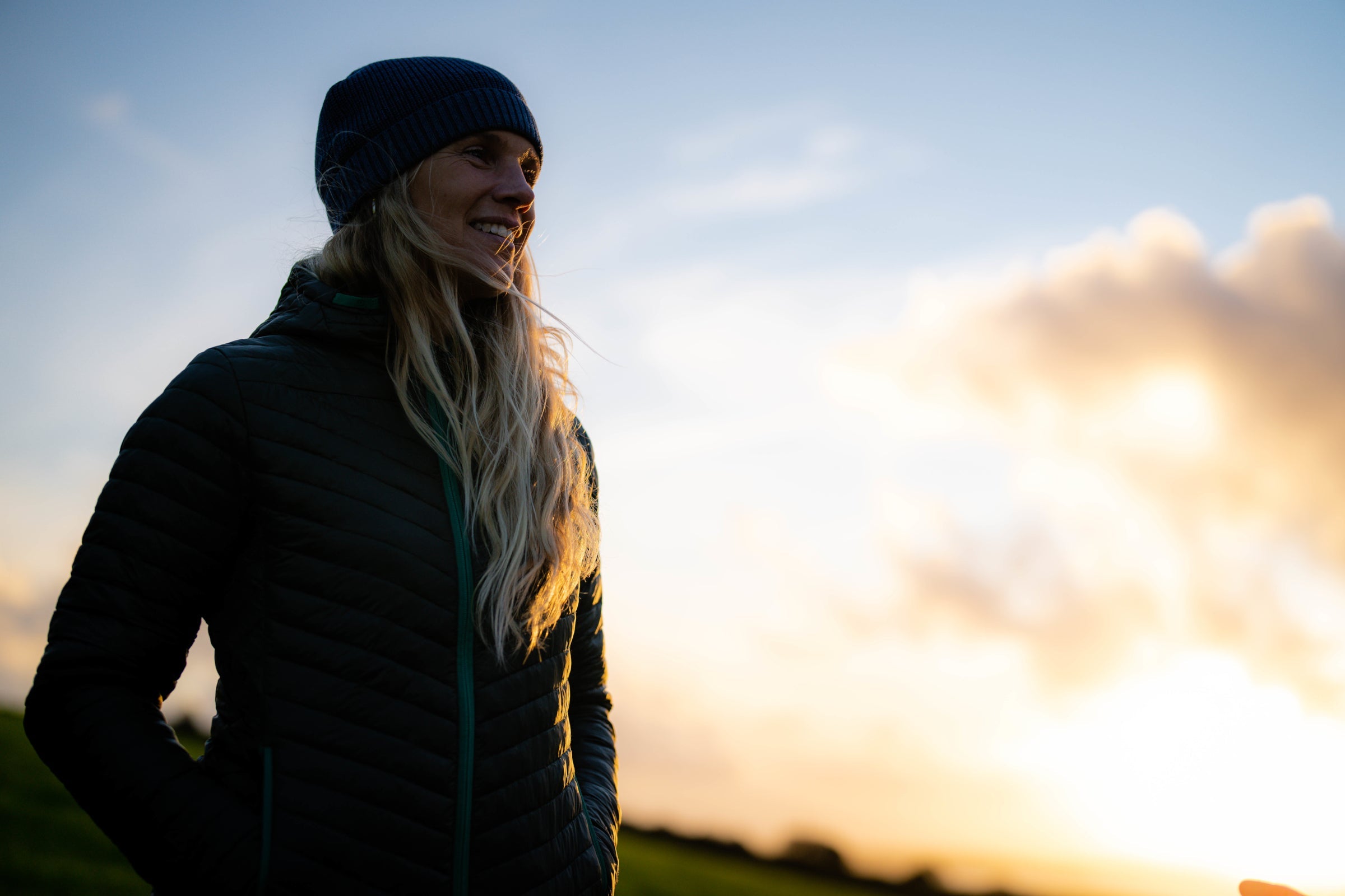 A person outdoors in warm clothing during sunset