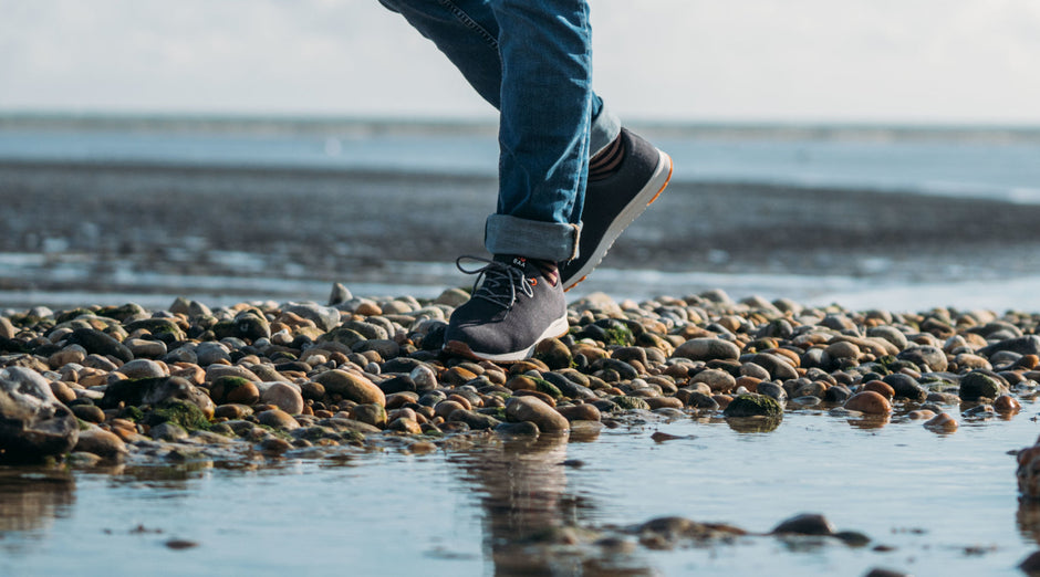 Isobaa Merino Wool Blend Trainers walking across a stony beach