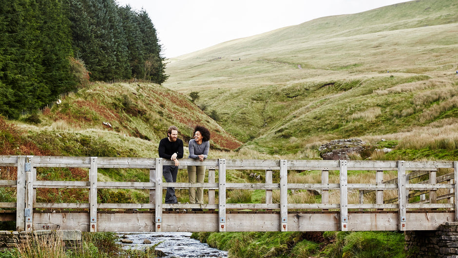 Isobaa Merino 180 Long Sleeve Crew Top worn on a wooden bridge over a stream