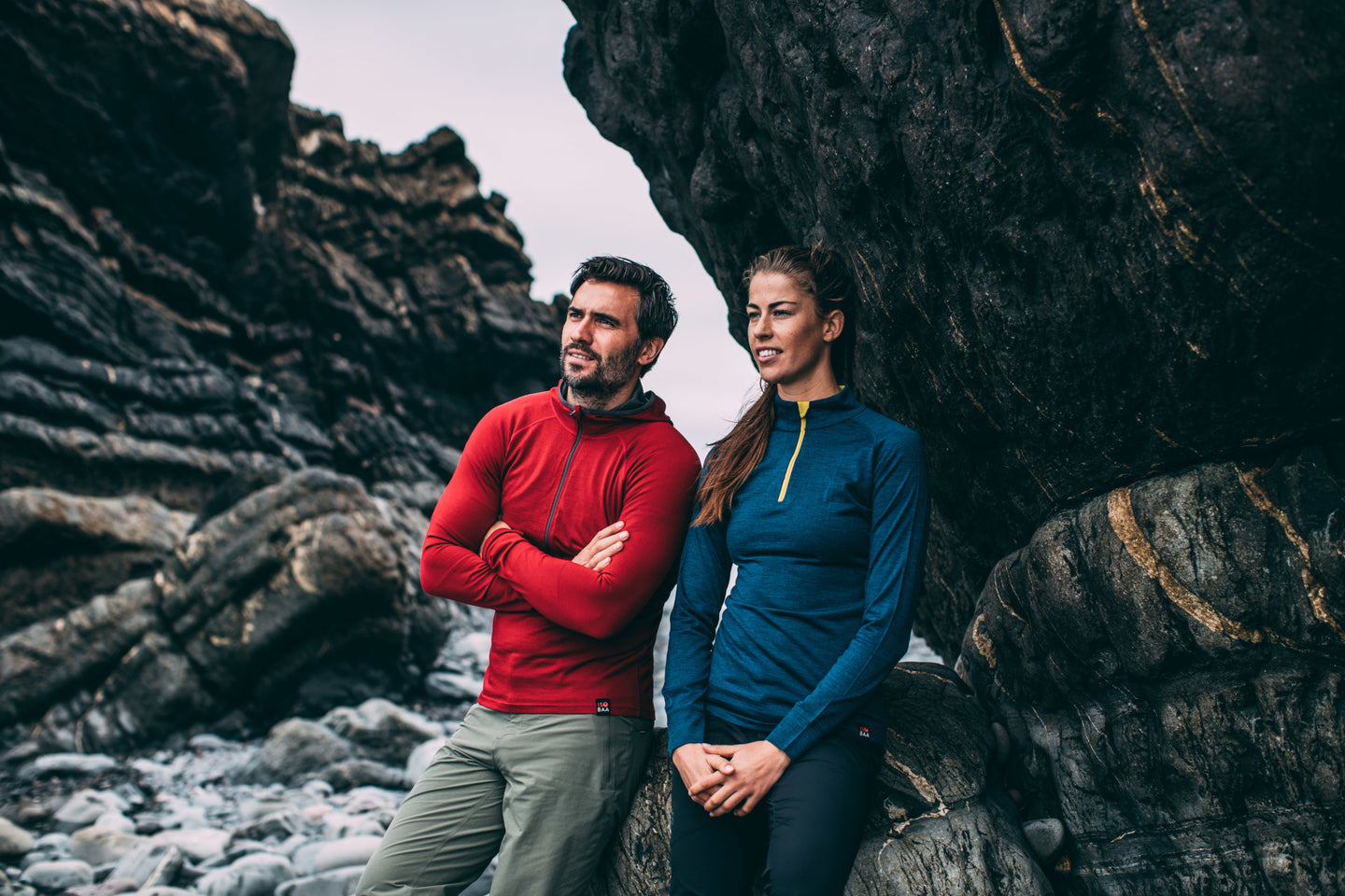 Two people wearing Isobaa merino base layers stand by rocky cliffs