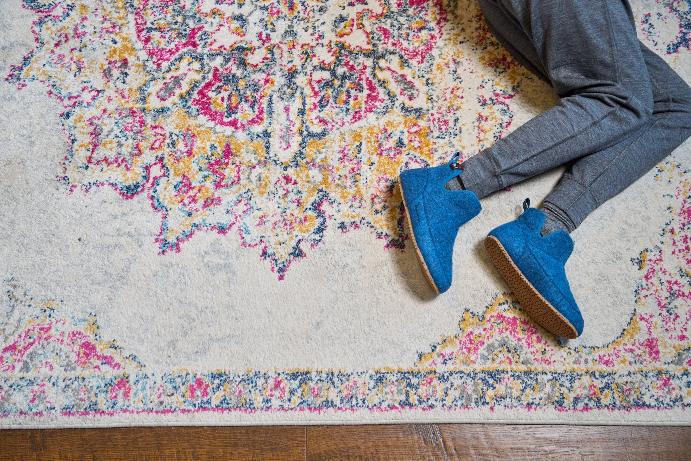 Blue merino blend slipper boots on a patterned rug, paired with grey loungewear