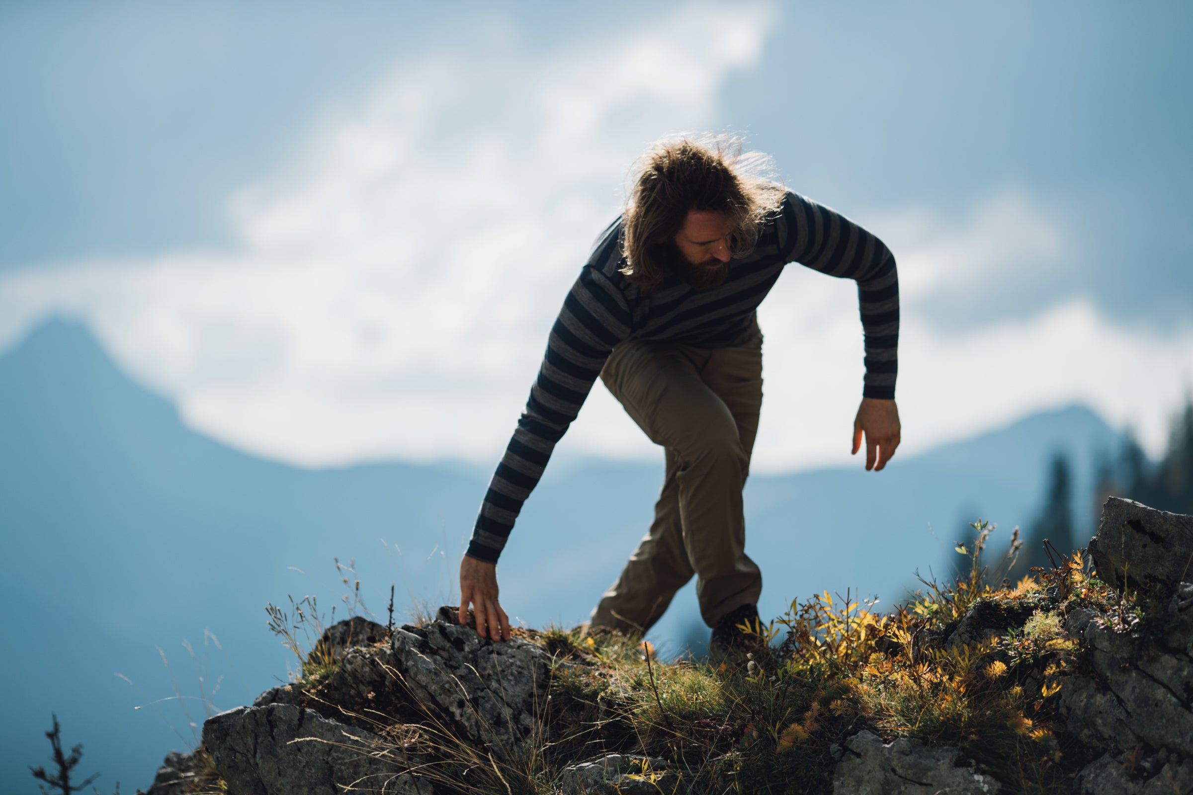 A man climbing up rocky terrain with mountains in the background